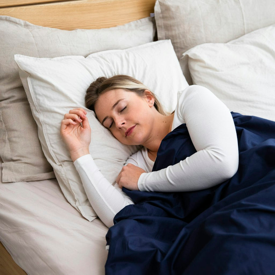 Woman sleeping on a bed with a blue blanket