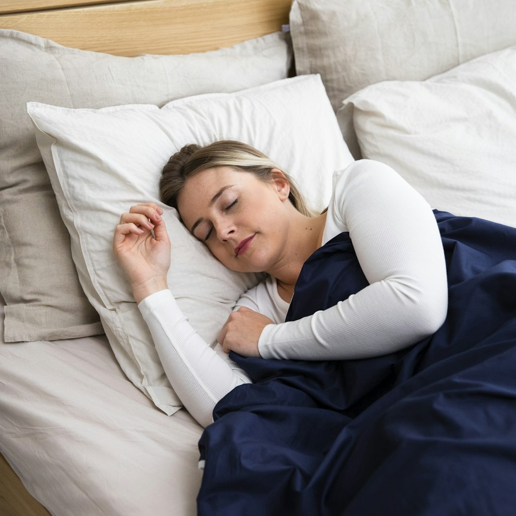 Woman sleeping on a bed with a blue blanket